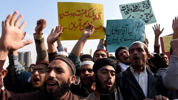 Students of Islamic seminaries hold placards reading in Urdu