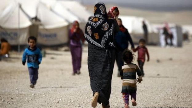 سيدة تحمل طفلا في أحد مخيمات اللاجئين قرب الحدود السورية العراقية