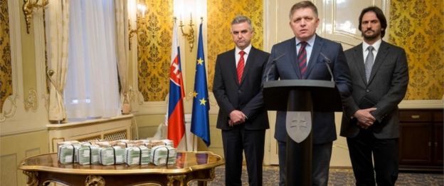 El ex primer ministro de Eslovaquia, Robert Fico, flanqueado por el director de la policía, Tibor Gaspar (izq.) y su ministro de Interior, Robert Kalinak, junto a una pila de billetes ofrecidos como recompensa.