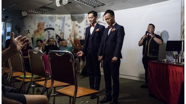 In this picture taken on May 5, 2018, pastor Joe Pang prays behind C.P. So (centre L) and Alvin Chan (centre R) during their wedding ceremony at a church in Hong Kong. - Same-sex marriage is not legally recognised in Hong Kong and often those who have a ceremony say they prefer to do it privately, away from the public gaze.