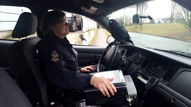 Canuck dentro de un auto policial con una agente