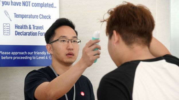 A volunteer (L) taking a temperature of a church member attending a small group service as a protective measure to prevent the spread of the COVID-19 coronavirus at the Heart of God church in Singapore.