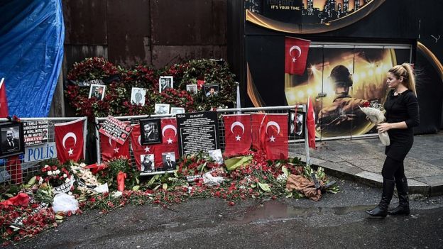 A woman lays flowers by a makeshift memorial in front of the Reina nightclub in Istanbul