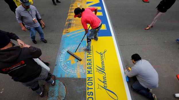 Crews install the decal marking the finish line on Boylston Street, for the 121st running of the Boston Marathon, in Boston, Massachusetts, U.S., April 13, 2017.