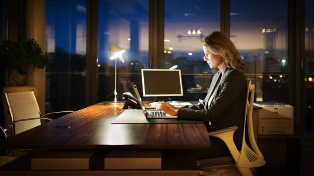 Una mujer trabajando de noche en una oficina solitaria
