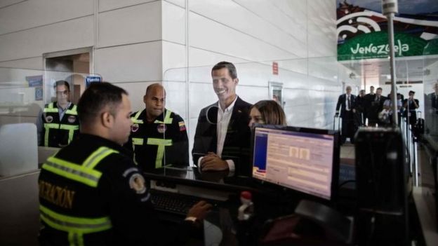 Handout photo released by Venezuelan opposition leader and self-proclaimed acting president Juan Guaido's official press showing him and his wife Fabiana Rosales checking passports at the migrations office of the International Simon Bolivar airport upon their arrival in Maiquetia