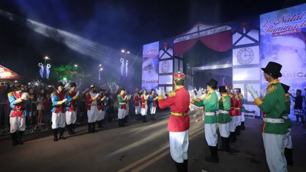 Dançarinos fantasiados participam de desfile noturno com tema de Natal