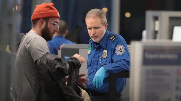 Um funcionário da Administração de Segurança no Transporte faz a triagem de passageiros e funcionários do aeroporto no Aeroporto Internacional O'Hare de Chicago