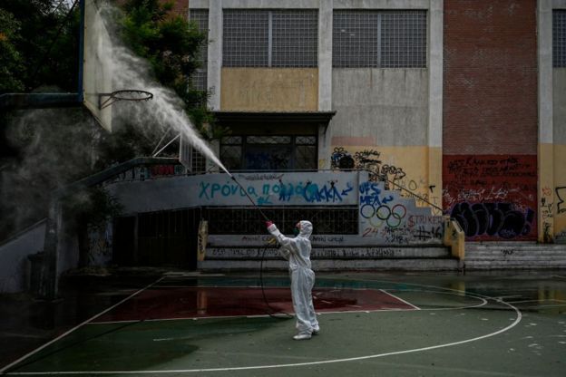 A municipality worker disinfects a high-school yard in Athens