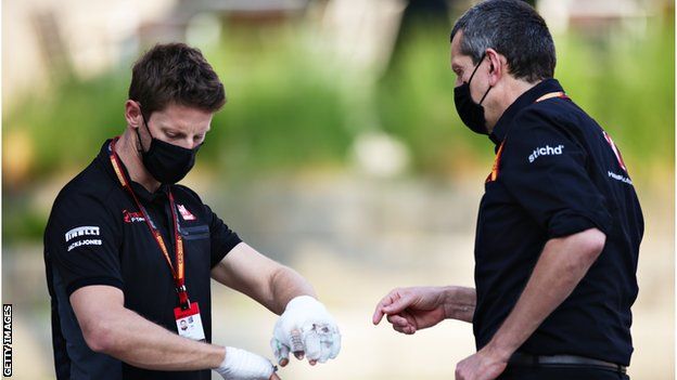 Roman Grosjean with bandaged hands talking to Haas F1 Team Principal Guenther Steiner