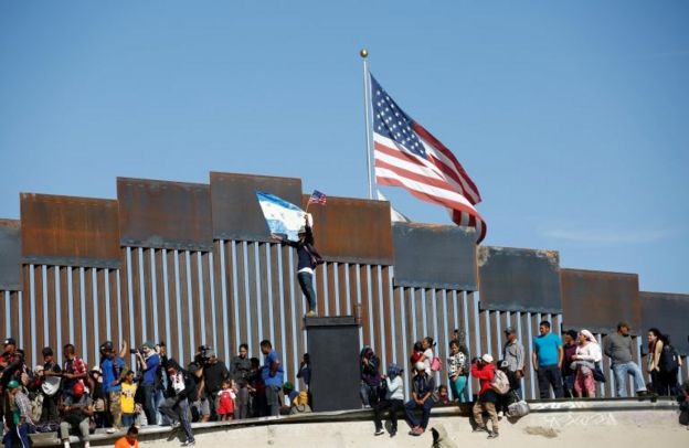 Migrantes junto al muro fronterizo en Tijuana