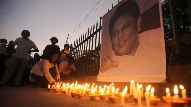 Sri Lankan journalists and well wishers light candles in front of a photograph of slain editor Lasantha Wickrematunge