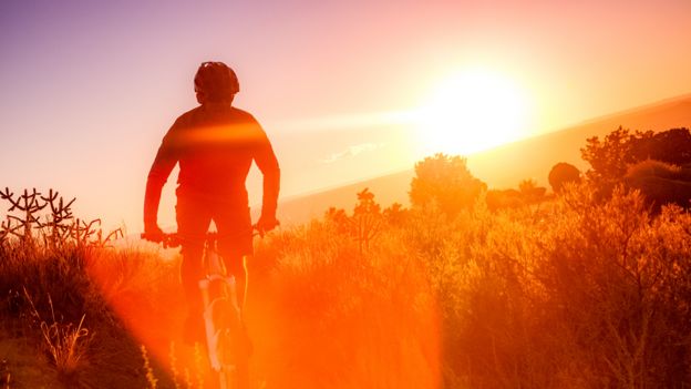 Hombre andando en bicicleta con una puesta de Sol de fondo