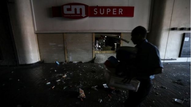 A shop employee helps clean up the area after the shop was looted during an ongoing blackout in Caracas, Venezuela, March 10, 2019.