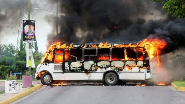 A burning bus, set alight by cartel gunmen to block a road, is pictured during clashes in Culiacán
