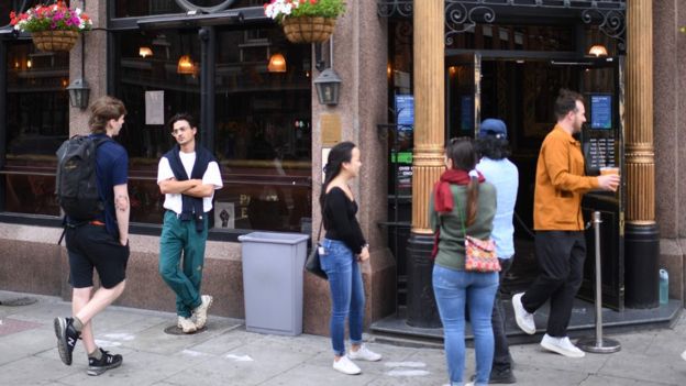 Customers queue outside a pub in east London