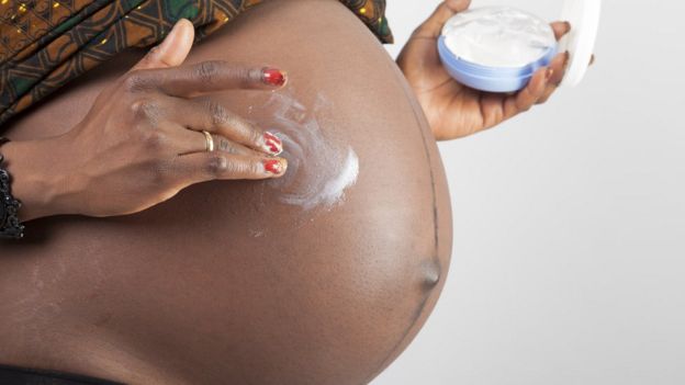 Embarazada aplicando crema en el vientre.