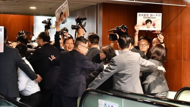 Security tries to control members of the press and protesting pro-democracy lawmakers after Carrie Lam had to leave the chamber for a second time