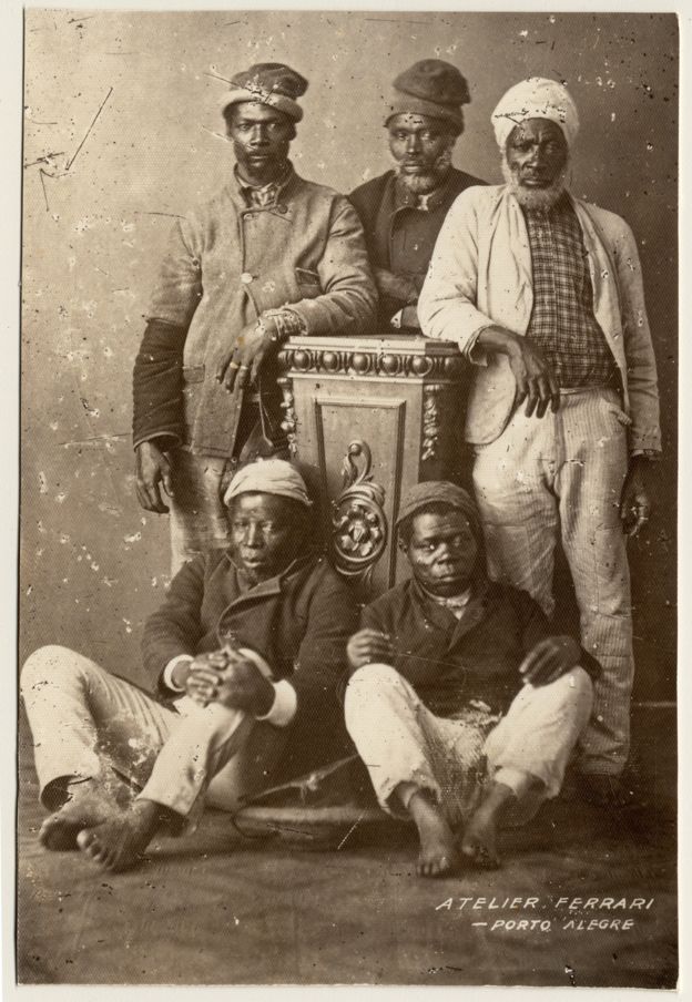 Imagem mostra três homens negros de pé e dois sentados. São ex-escravos fotografados em um estúdio de Porto Alegre no final do século XIX. Crédito: Acervo do Museu de Porto Alegre Joaquim Felizardo/Irmãos Ferrari