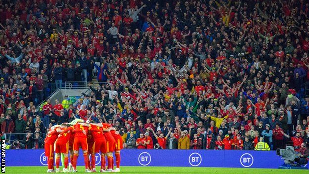 Wales players get together in a huddle in front of their fans at Cardiff City Stadium