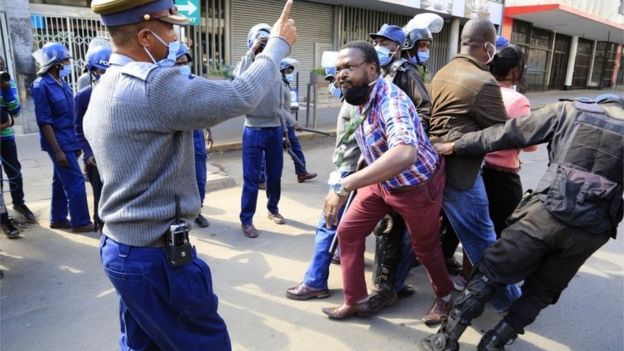 Police officers watch Movement For Democratic Change (MDC) Alliance youth leader Lovemore Chinoputsa is dragged by police officers outside the party headquarters in Harare, Zimbabwe, 05 June 2020