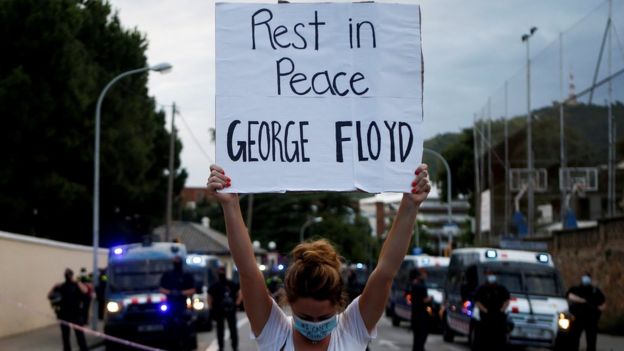 A woman holds a sign reading "Rest in peace George Floyd" outside the US consulate in Barcelona