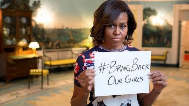 Michelle Obama sosteniendo un letrero que dice 