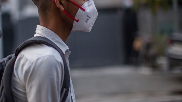 A Delhi school boy with a shoulder bag looks on