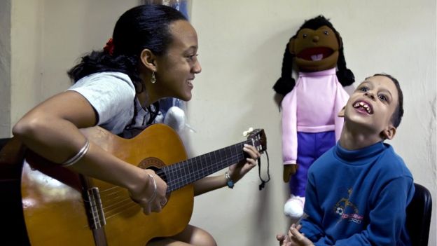 Cô giáo và chuyên gia điều trị chơi ghi ta cho một trẻ tự kỷ tại Trường đặc biệt Dora Alonso ở Havana, Cuba.