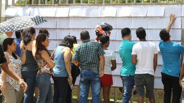 Colombianos buscando su mesa de votación en un panel.