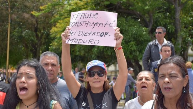 A woman holds up a sign at an anti-government protest in Merida reading: