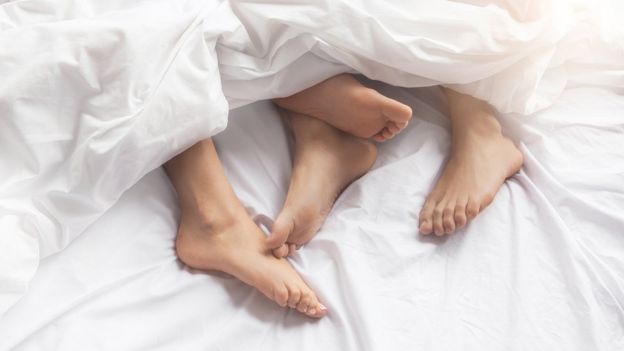 Dos pares de pies en una cama.