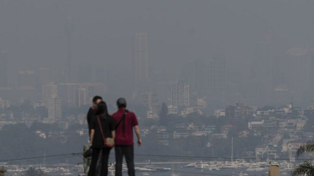 Tourists take in a hazy view of Sydney's skyline amid intense bushfires north of the city