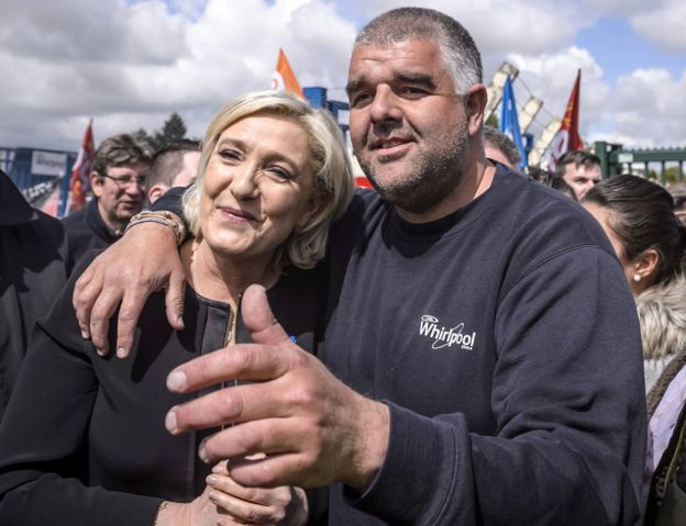 Marine Le Pen (L) poses for photographs with an unidentified supporter (R) and Whirlpool employees outside the Whirlpool plant in Amiens, northern France, 26 April 2017