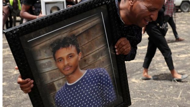 A relative carries a portrait of Yared Getachew, pilot of the crashed Ethiopian Airlines Boeing 737 Max, 14 March 2019