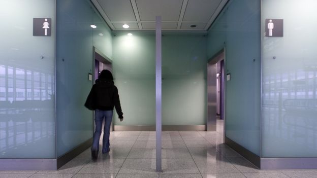 Una mujer entrando a un baño público.