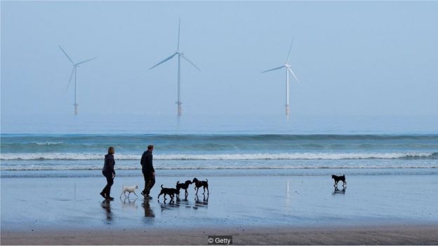 Pessoas caminhan na praia