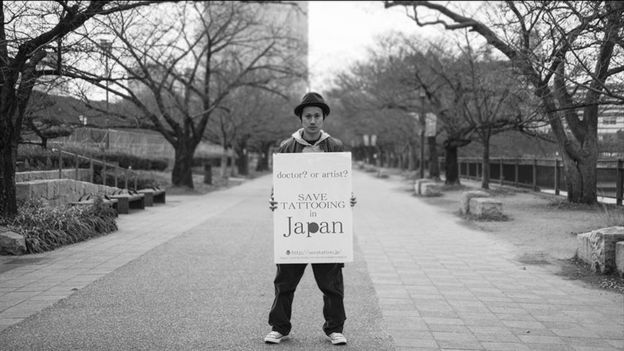 Tattoo artist holding up protest sign