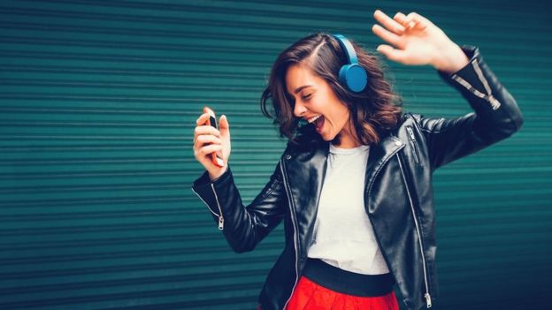 Una chica alegre bailando con cascos.