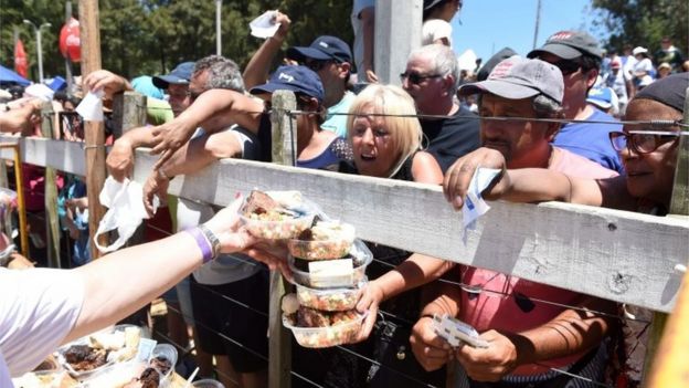 Crowds wait for trays of barbecued beef as a total of 16,500 kg of beef are grilled in Rodo Park in Minas, Uruguay, 120 km from Montevideo, in an attempt to break the Guinness record for 