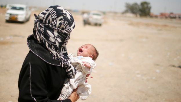 A displaced Iraqi holds her baby while she moves to a safe place as Iraqi forces battle Islamic State militants in western Mosul (10 May 2017)