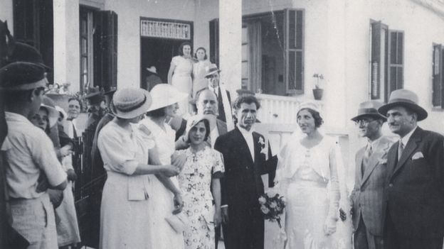 black and white photo of a wedding party gathering in front of the house