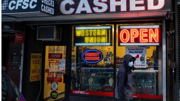 Hombre con mascarilla pasa frente a una sucursal de Western Union