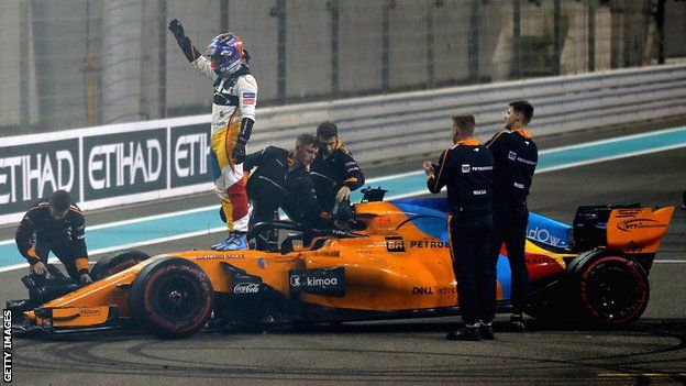 Fernando Alonso waves to the crowd while standing on his McLaren car after the end of his final Grand Prix before retirement in Abu Dhabi