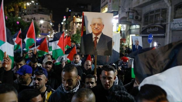 Palestinian protesters wave the national flag and a portrait of president Mahmud Abbas during a demonstration in the West Bank city of Ramallah on January 28, 2020