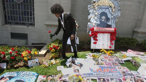 A man adjusts a flower at a memorial to Michael Jackson