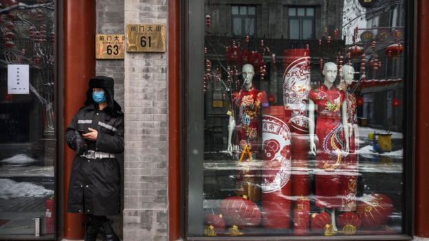 A guard stands outside a closed shop in Beijing