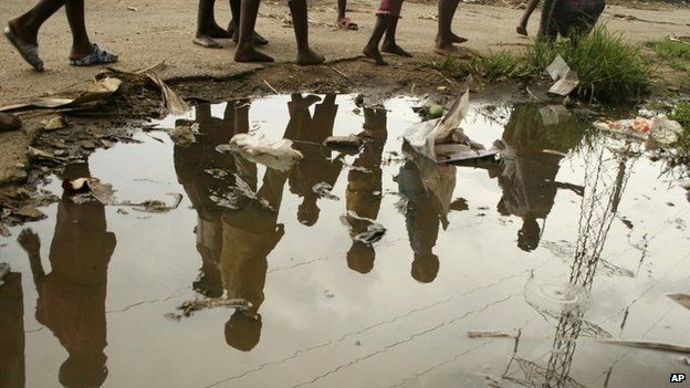 children walk past puddle in harare