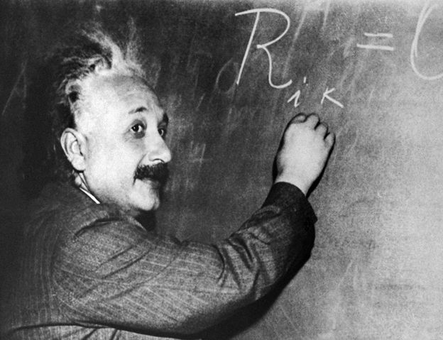 Albert Einstein writing an equation on a blackboard