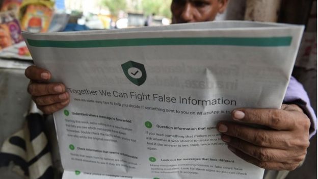 In this file photo illustration taken on July 10, 2018 shows an Indian newspaper vendor reading a newspaper with a full back page advertisement from WhatsApp intended to counter fake information, in New Delhi.